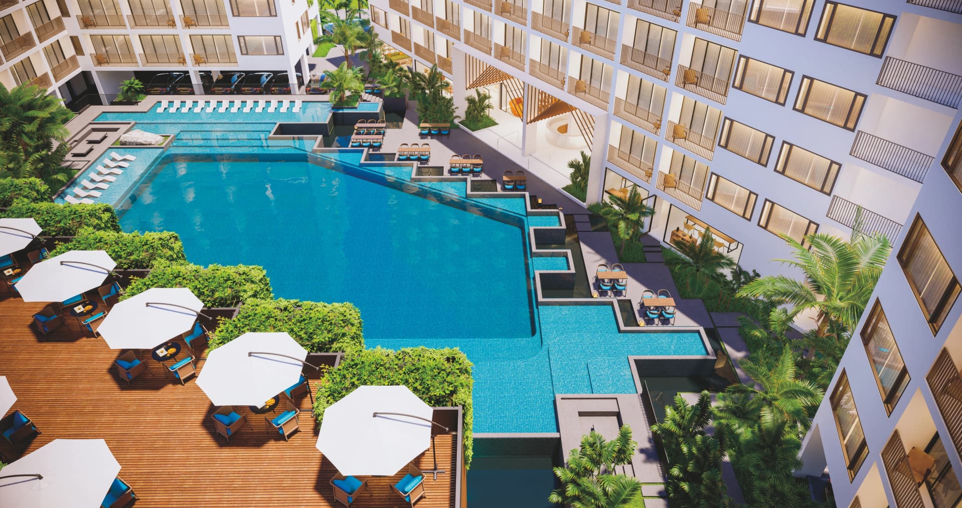 The courtyard from above: the zig-zag turquoise pool, the timber deck with white parasols and the apartment wings